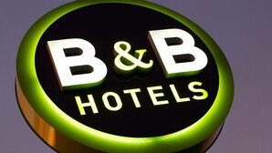 A circular sign with the text "B&B HOTELS" against a purple sky.