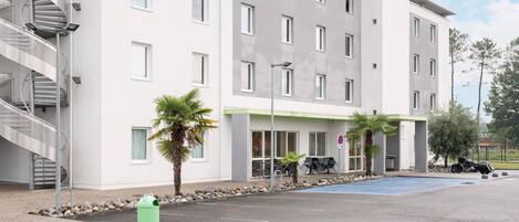 A modern hotel with a spiral staircase, a parking area, and a sign indicating no parking.
