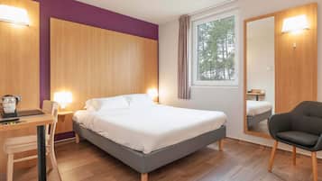 Una habitación de hotel moderna con cama, escritorio, silla y un espejo grande.