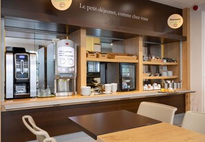 Un café équipé d’une machine à café, d’un réfrigérateur et d’un présentoir où sont exposés des produits pour le petit-déjeuner.