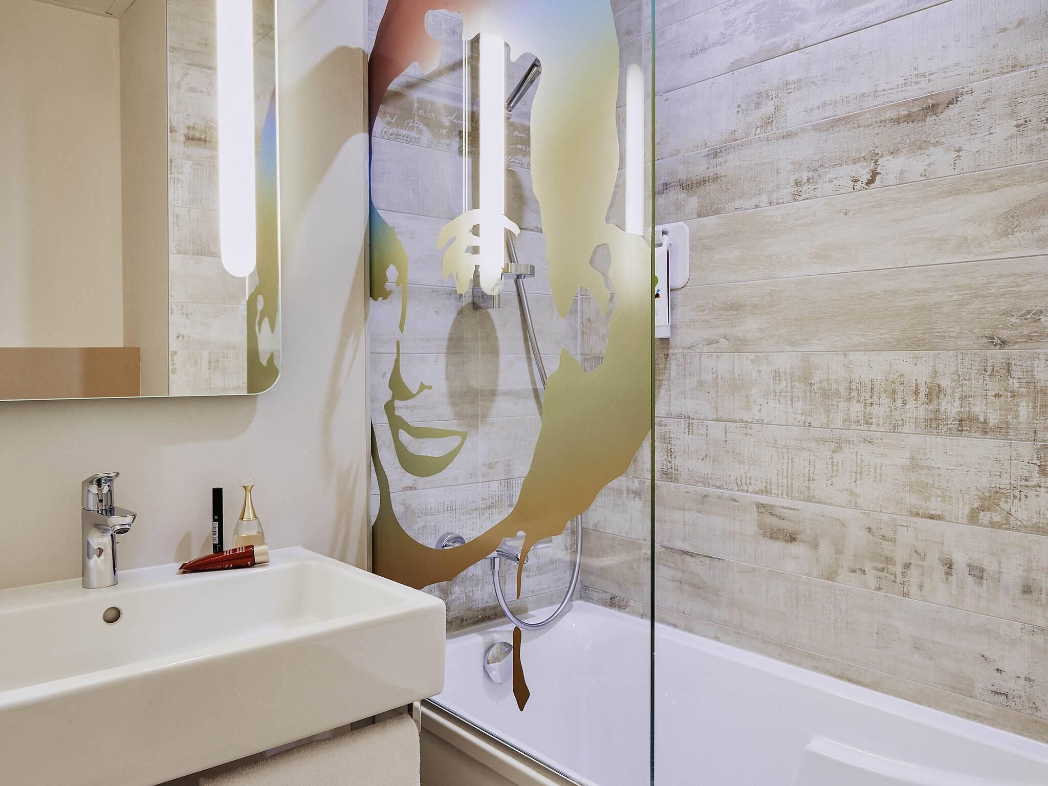 A bathroom with a white sink, a mirror, and a shower with a glass partition.