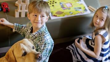 Un niño y un perro sentados en un sofá con juguetes y un mapa al fondo.