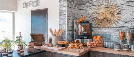 Zona de recepción con mostrador que exhibe pasteles, una máquina de café y un mural en la pared.