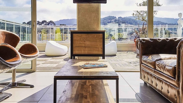 Un espacio lounge moderno con una mesa de centro de madera, sofá de cuero y sillones tipo frijol blancos.