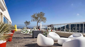 Terraza en la azotea con mobiliario moderno, plantas en macetas y vistas a la ciudad.