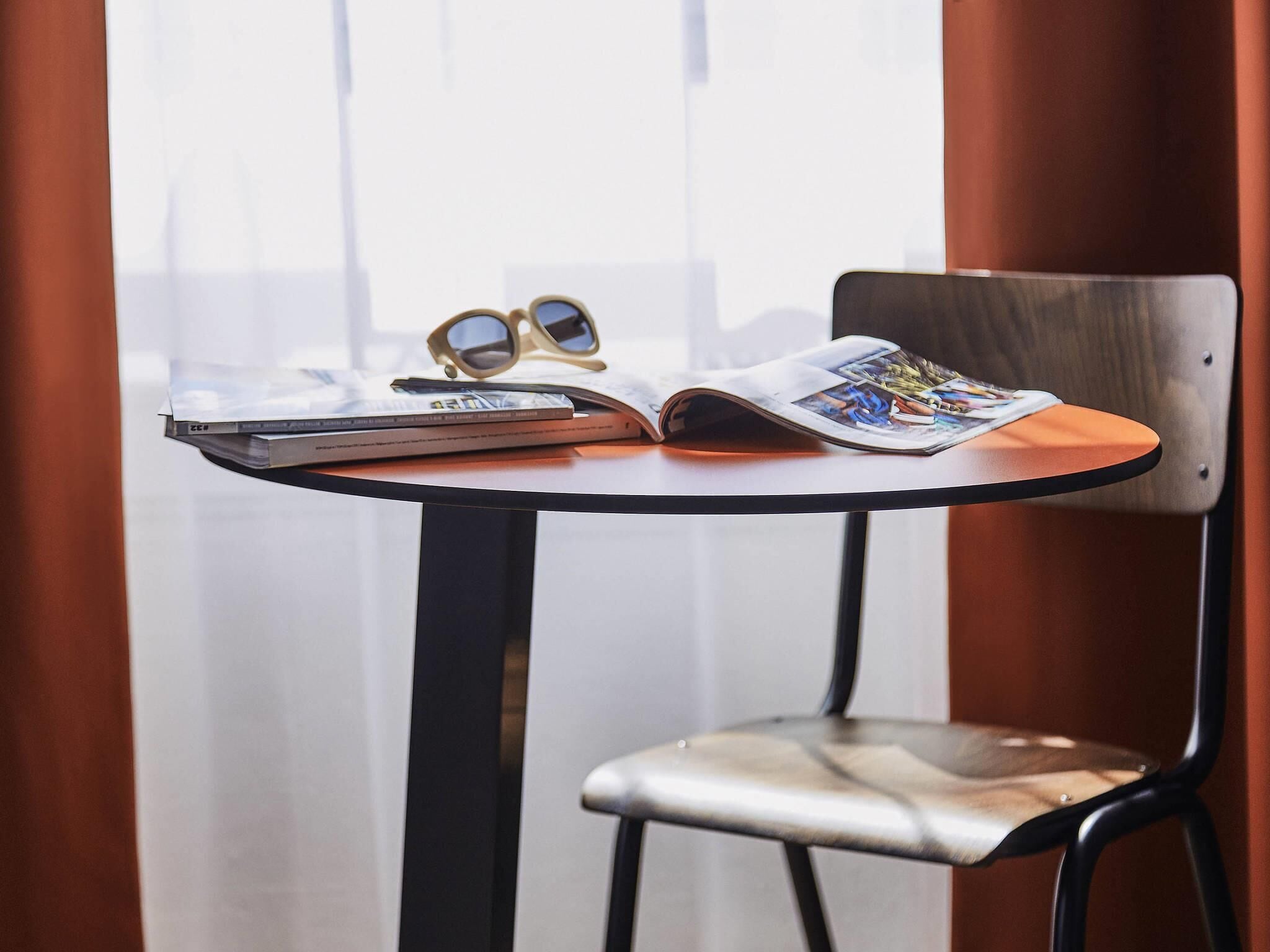 A table with a magazine, a pair of sunglasses, and a notebook.
