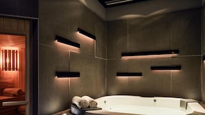 Un baño moderno con una bañera independiente, estantes empotrados y un banco de madera.