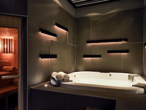 A modern bathroom with a freestanding bathtub, built-in shelves, and a wooden bench.