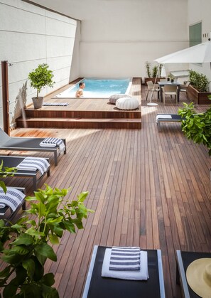 A wooden deck with a hot tub, lounge chairs, and a table with chairs. - Eric Vökel Boutique Apartments - Atocha Suites (Madrid)