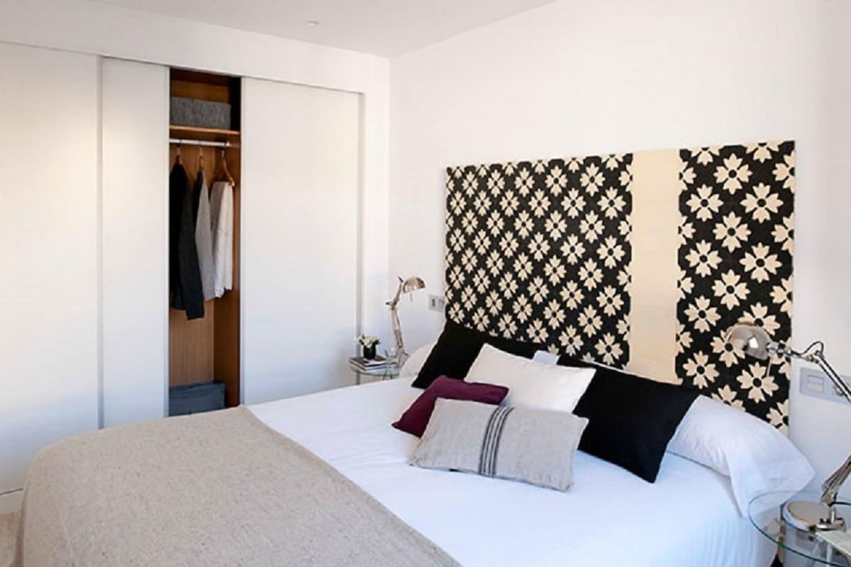 A bedroom with a bed, a bedside table, a lamp, and a wardrobe.