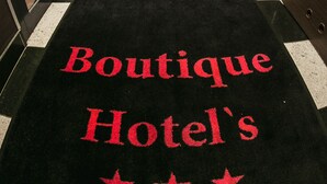 A hotel corridor with a black carpet featuring the text "Boutique Hotel's" and three stars. - Boutique Hotel’s I Milionowa (Lodz)