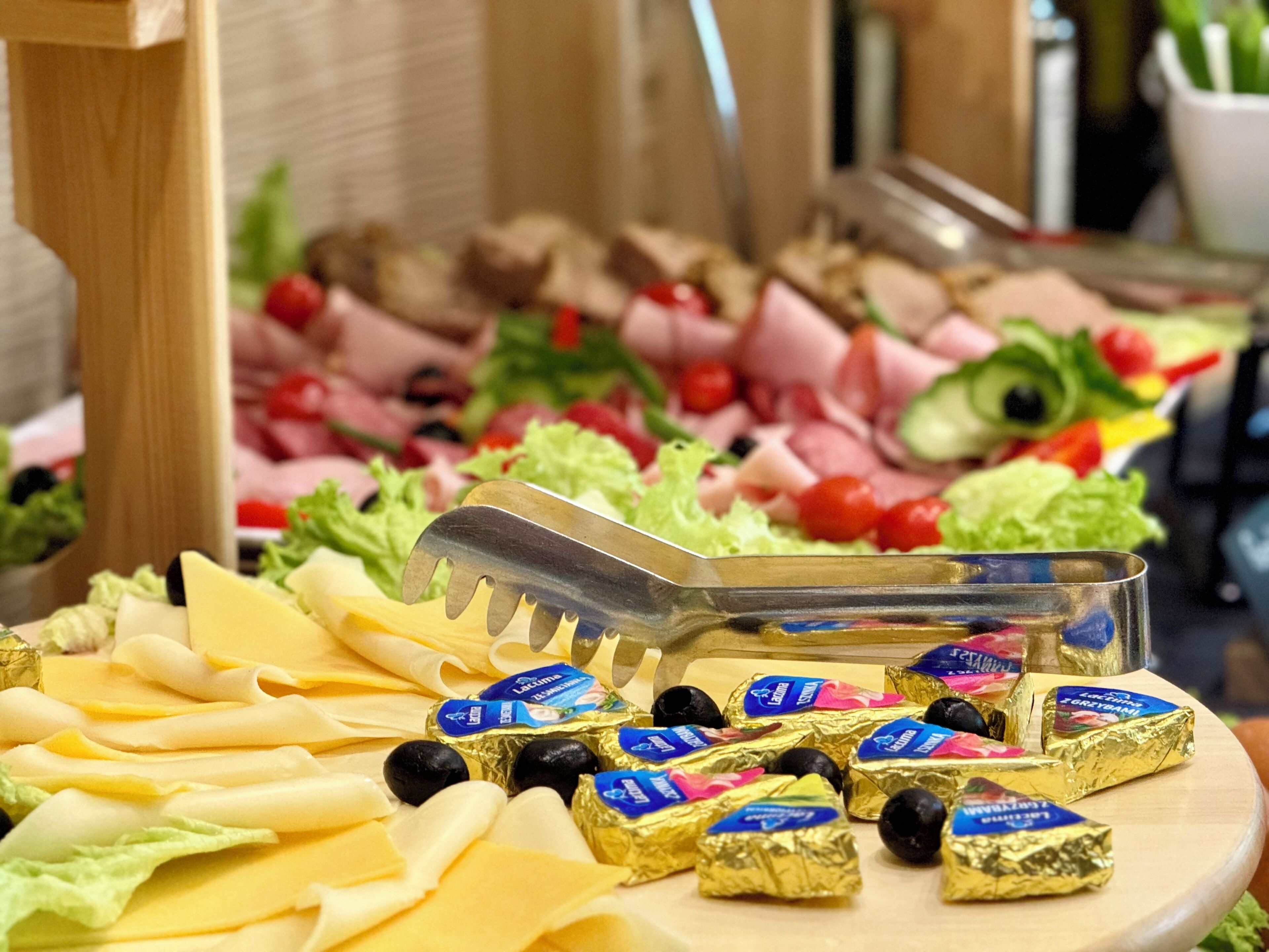 A buffet table with various cheeses, olives, and packaged chocolates.