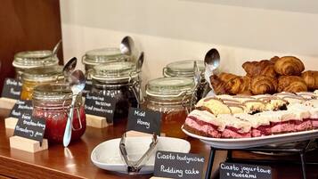 A variety of food items including jars of jam, honey, and cakes, with labels in a foreign language.