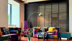 A modern living room with a colorful sofa set, a glass coffee table, and a large window with blinds. - Boutique Hotel’s I Milionowa (Lodz)