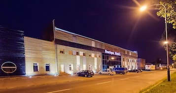A building with a sign reading "Boutique Hotel's" at night, featuring a modern design with large windows and a parking lot with several cars.