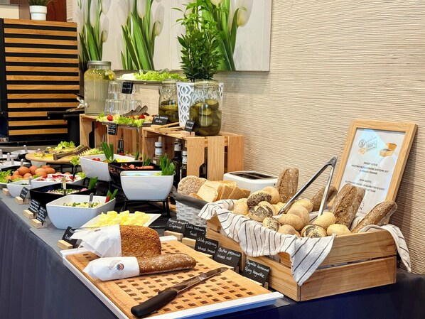 Un bufé con diversos alimentos, incluyendo pan, ensaladas y salsas.