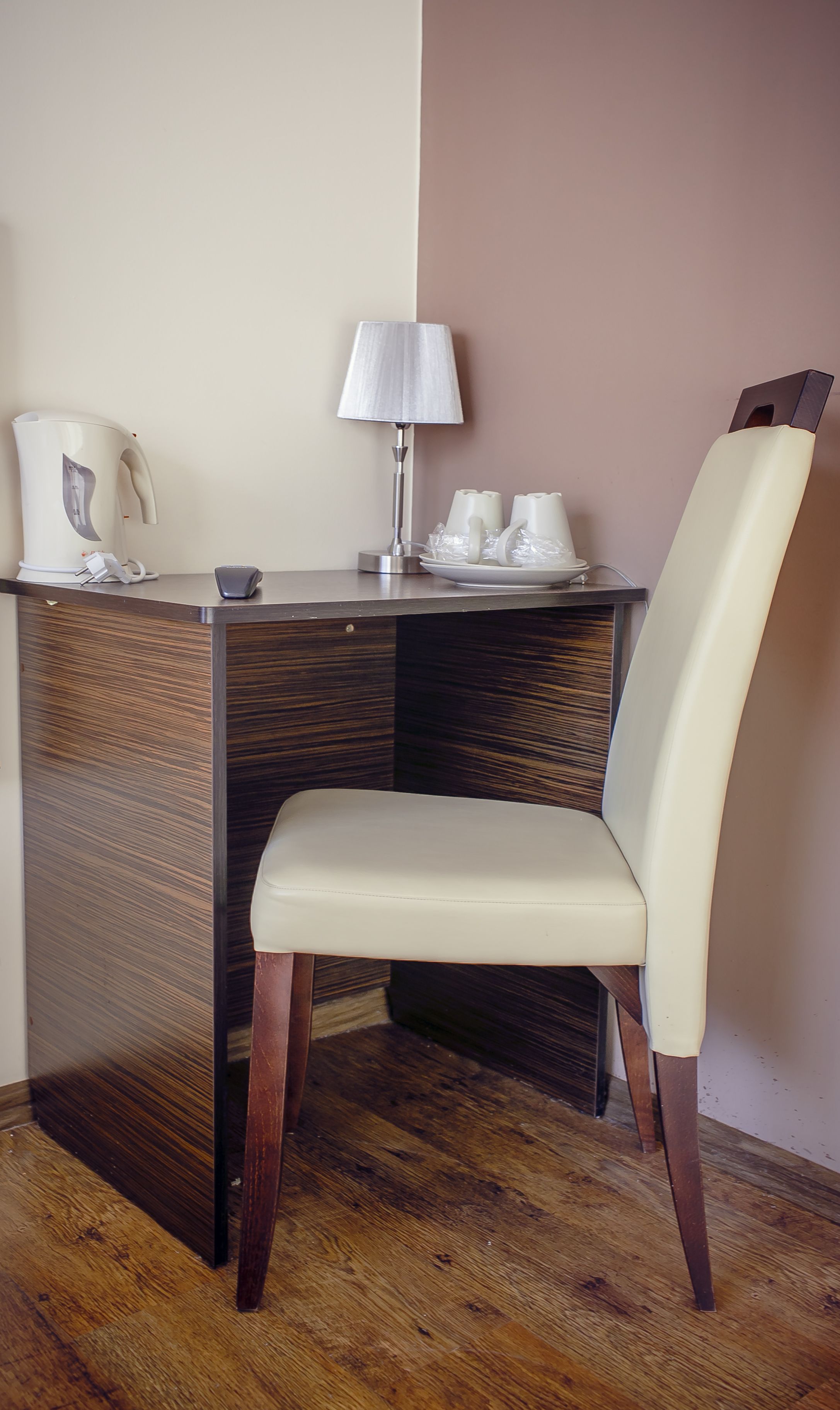 Un bureau en bois avec une lampe, une chaise blanche et une machine à café.