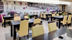 A modern restaurant with multiple tables and chairs, a mural on the wall, and potted plants. - Boutique Hotel’s II Rewolucji (Lodz)
