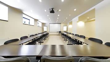 A conference room with long tables and chairs, a projector, and a whiteboard.