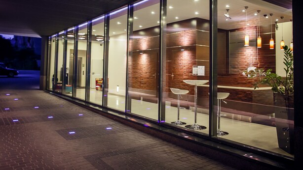 A modern building exterior with glass doors, a brick wall, and a reception area with a counter and chairs. - Boutique Hotel’s II Rewolucji (Lodz)