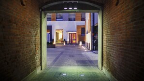 A narrow brick alleyway leading to a building with a modern facade, illuminated by overhead lights. - Boutique Hotel’s II Rewolucji (Lodz)