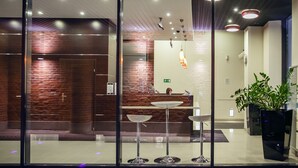 A modern reception area with a brick wall, a reception desk, and a potted plant. - Boutique Hotel’s II Rewolucji (Lodz)