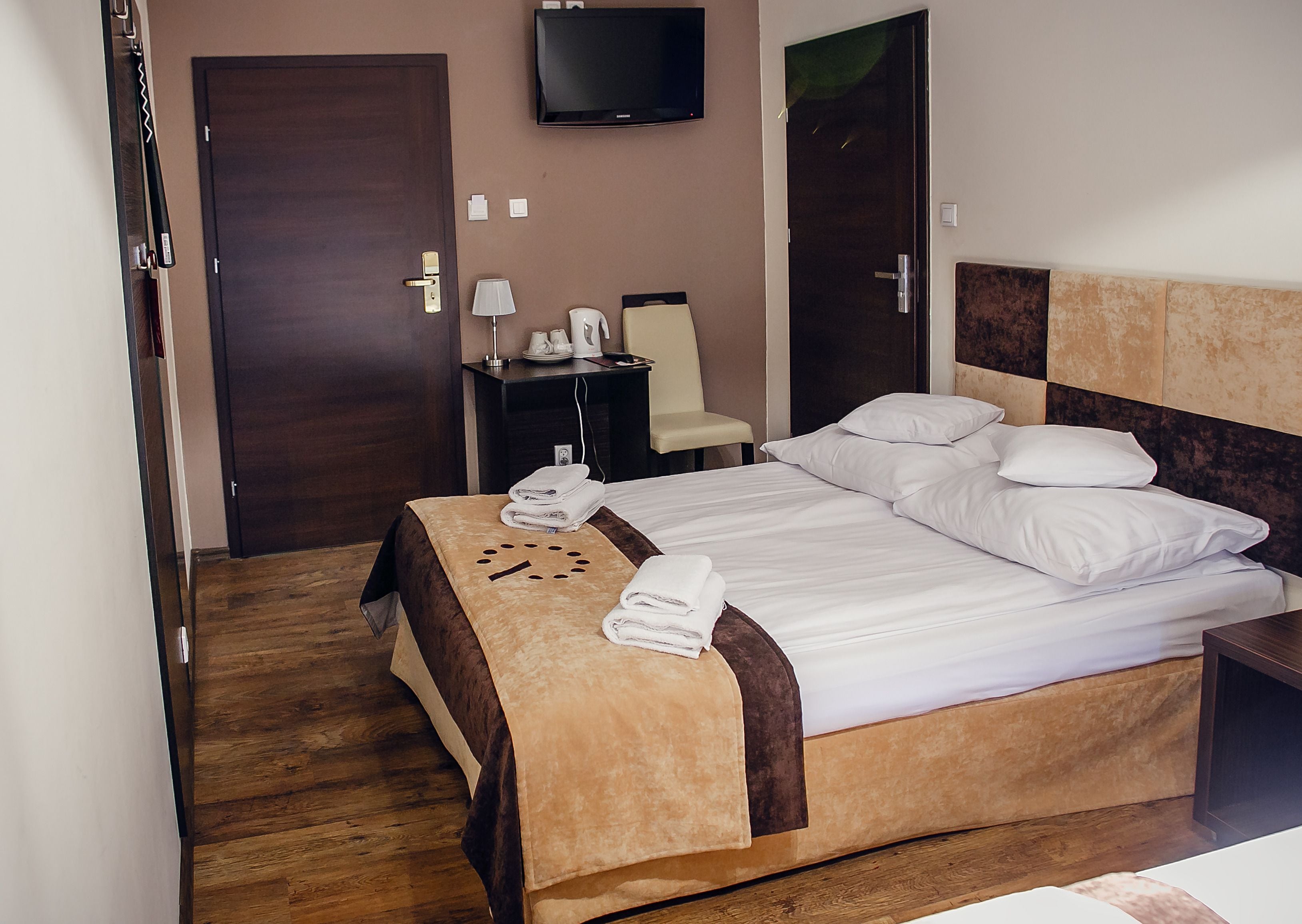 Une chambre d’hôtel avec un lit, une table de chevet, une télévision et une porte.