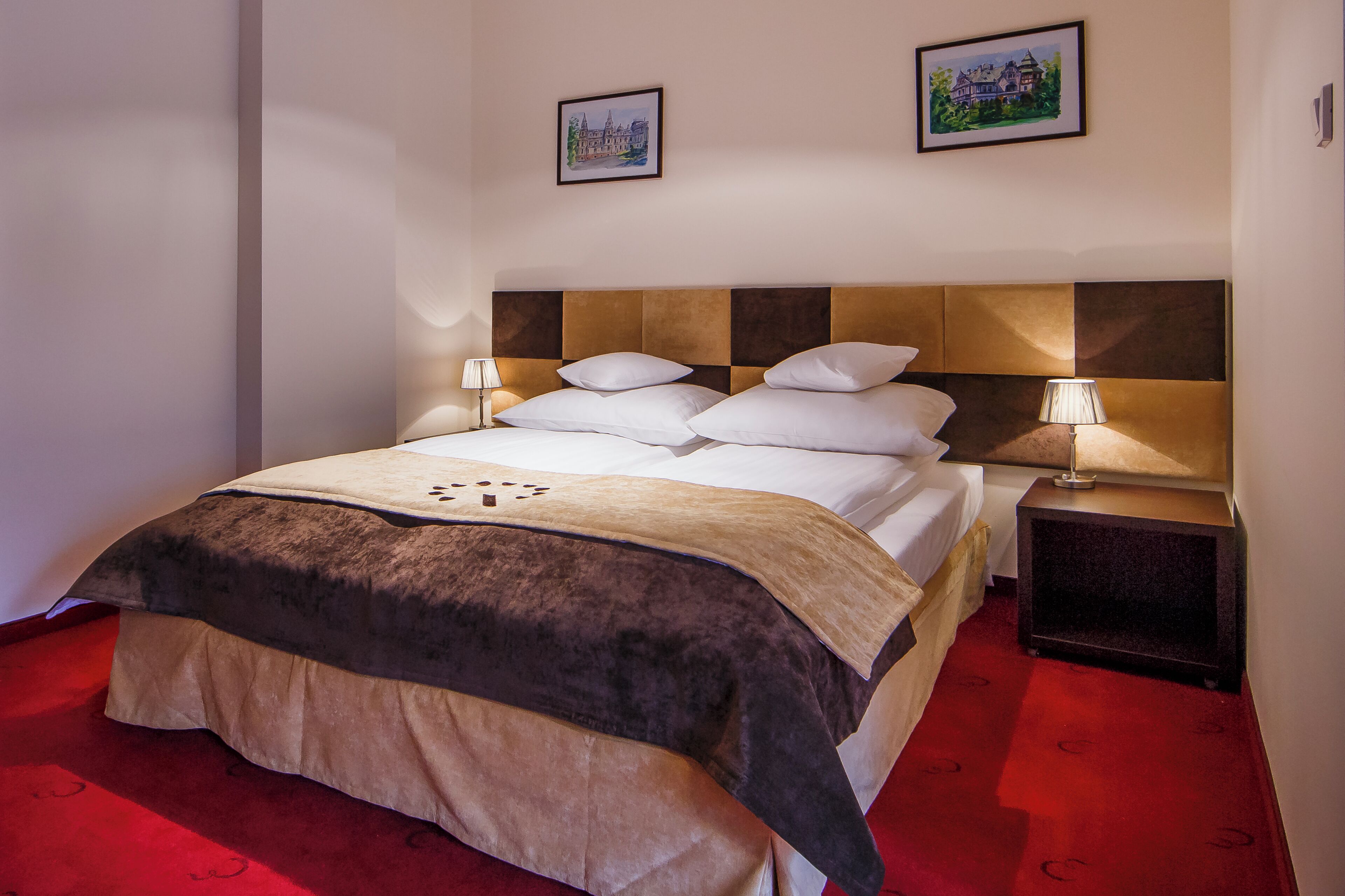 A neatly made bed with a brown and white duvet, two bedside lamps, and a framed picture on the wall.
