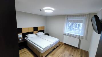 Quarto de hotel com cama, mesa de cabeceira, abajur, janela com vista e luminária no teto.