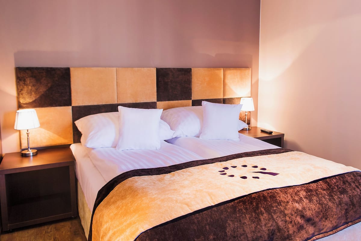 A hotel room with a bed, two bedside tables, a lamp on each table, and a headboard with a checkered pattern.