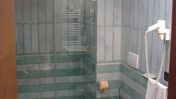 Un baño con cabina de ducha de vidrio, inodoro y lavamanos.