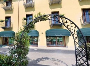 A yellow building with a green awning, a metal archway, and a window with a sign that reads "Azzurri Riva".