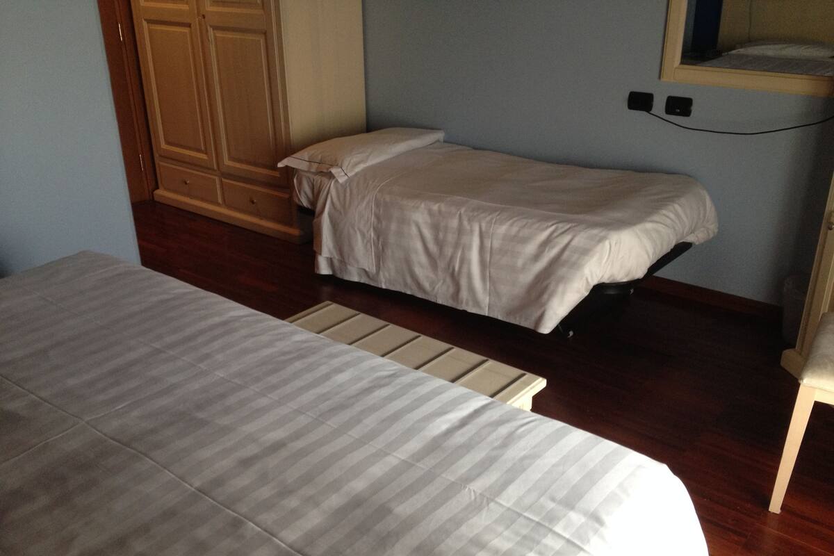 Une chambre avec deux lits, un plancher en bois, une armoire et un miroir.