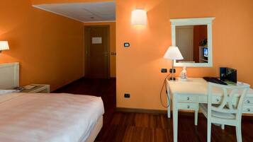 Una habitación de hotel con una cama, un escritorio con silla, una lámpara y un televisor.
