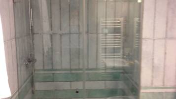 A shower stall with a glass door, tiled walls, and a white floor.
