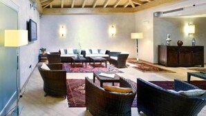A spacious living area with a high ceiling and exposed beams, furnished with wicker chairs and tables, and a central coffee table. - Hotel Ristorante Vecchia Riva (Varese)