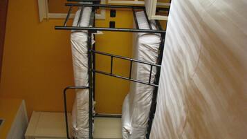 A bunk bed with white bedding in a room with yellow walls.