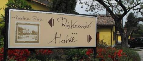 A sign for a hotel named "Ristorante Hotel" with a vintage photo and directional arrows.
