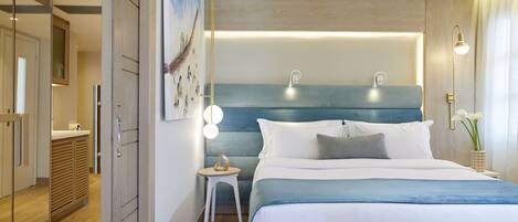 Una habitación de hotel moderna con una cama grande, lámparas de noche, una mesita auxiliar pequeña y un espejo.