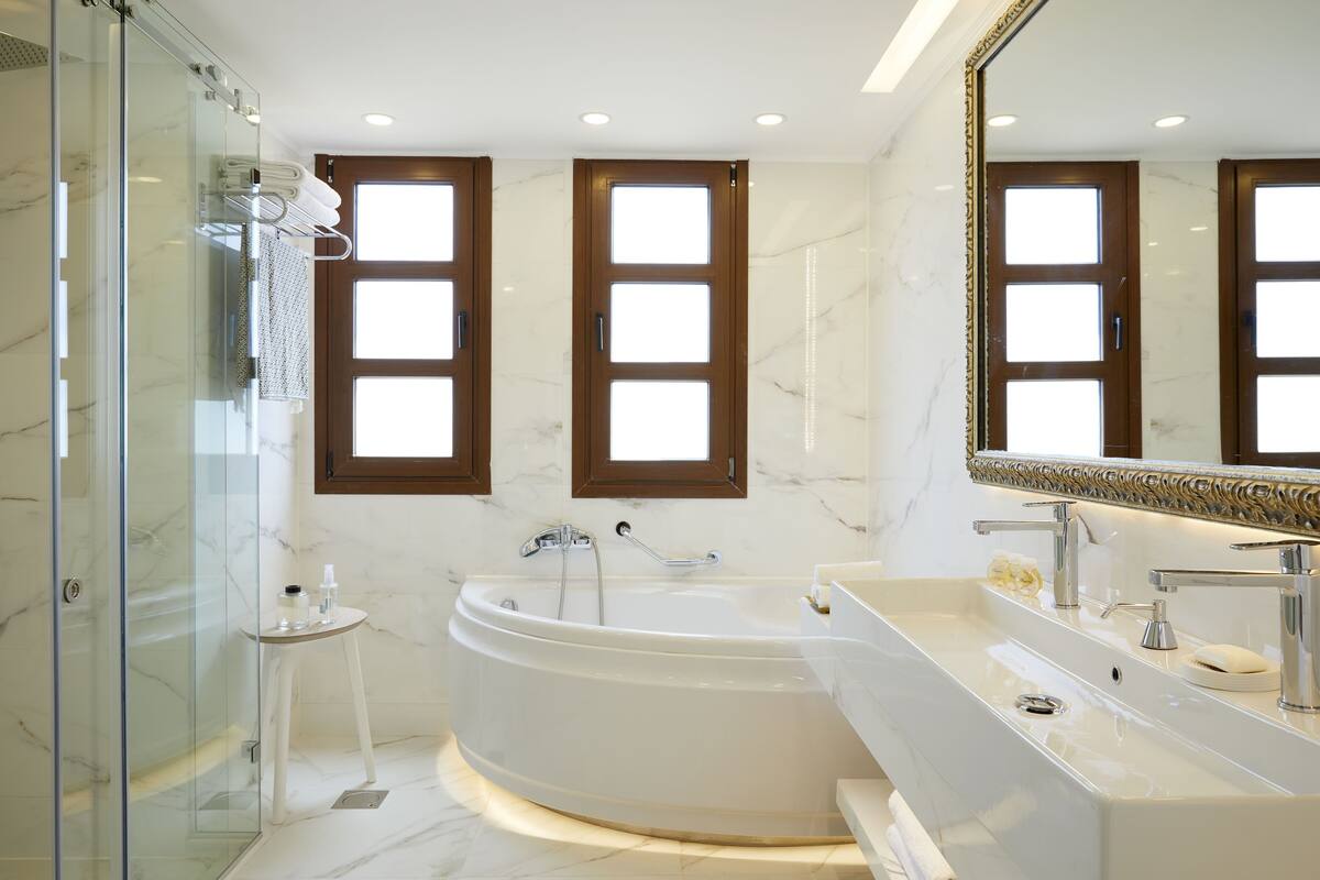 A modern bathroom with a glass-enclosed shower, a freestanding bathtub, and a vanity with a large mirror.