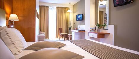 A hotel room with a bed, a desk, a chair, a television, and a mirror.
