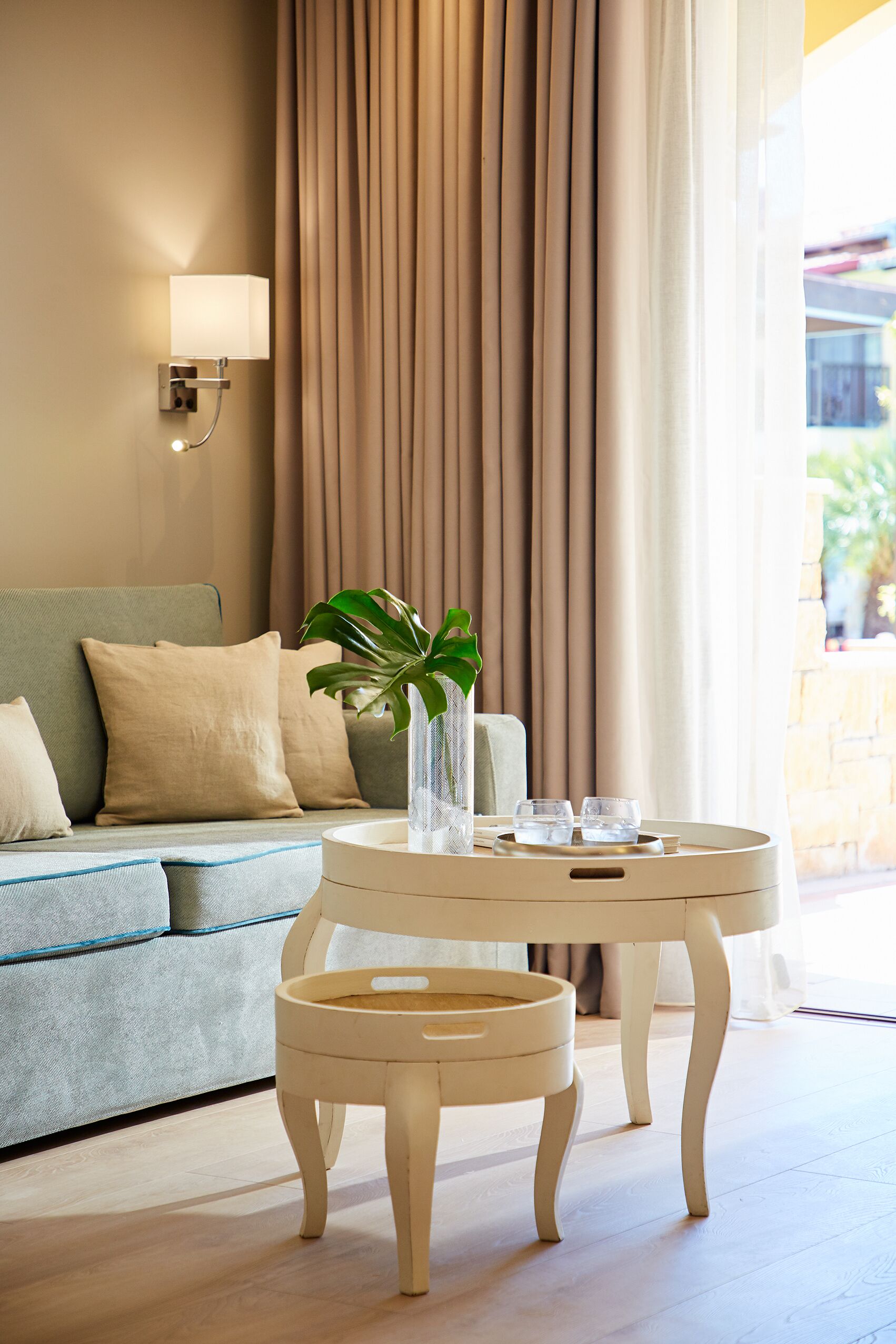 A modern living room with a sofa, a small round table, and a potted plant.