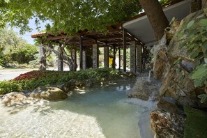 A covered outdoor area with a water feature, stone pillars, and greenery. - Anthemus Sea Beach Hotel & Spa (Sithonia)