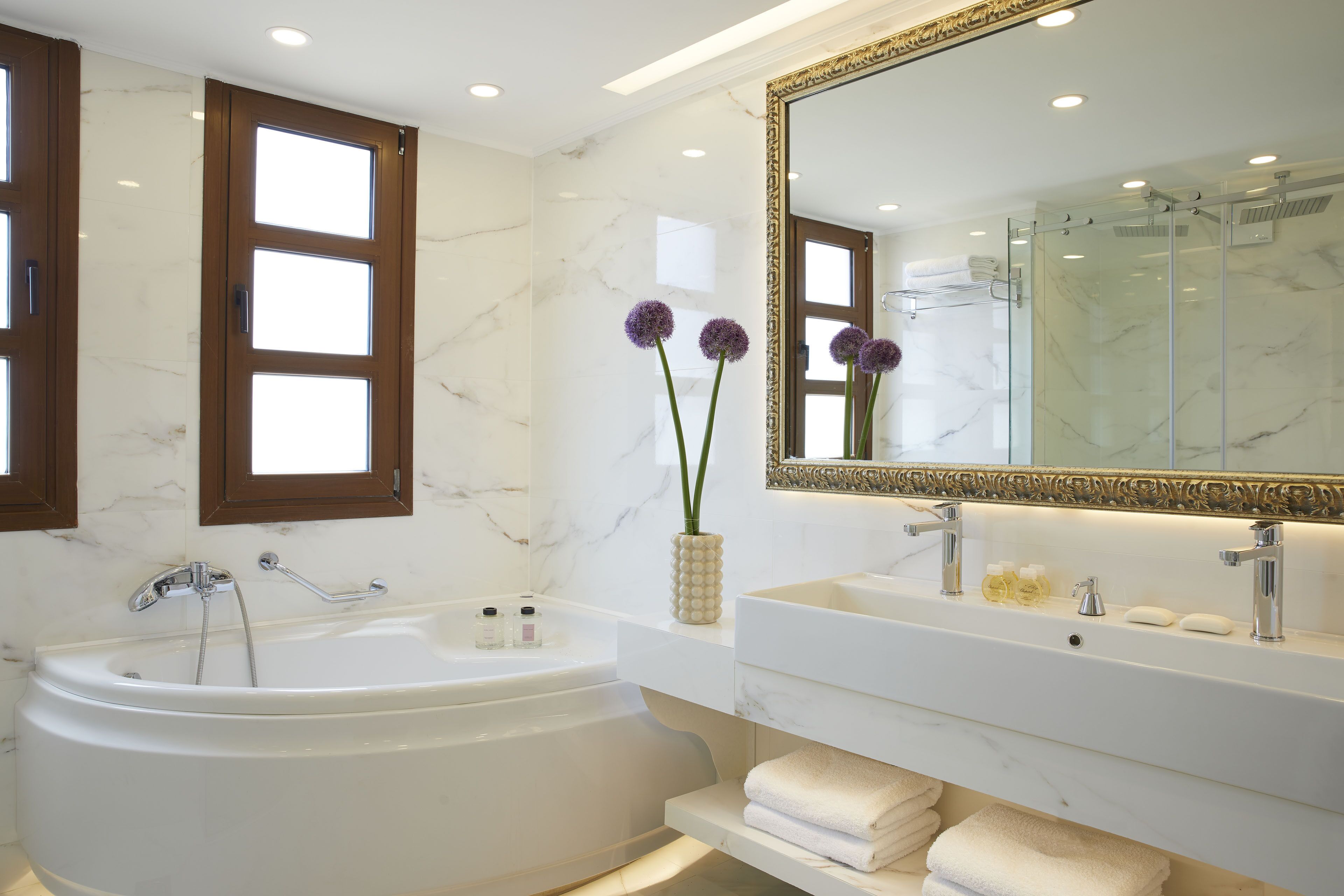 Une salle de bain moderne avec une baignoire sur pieds, un grand miroir et un meuble-lavabo doté d’un évier et d’un porte-serviettes.