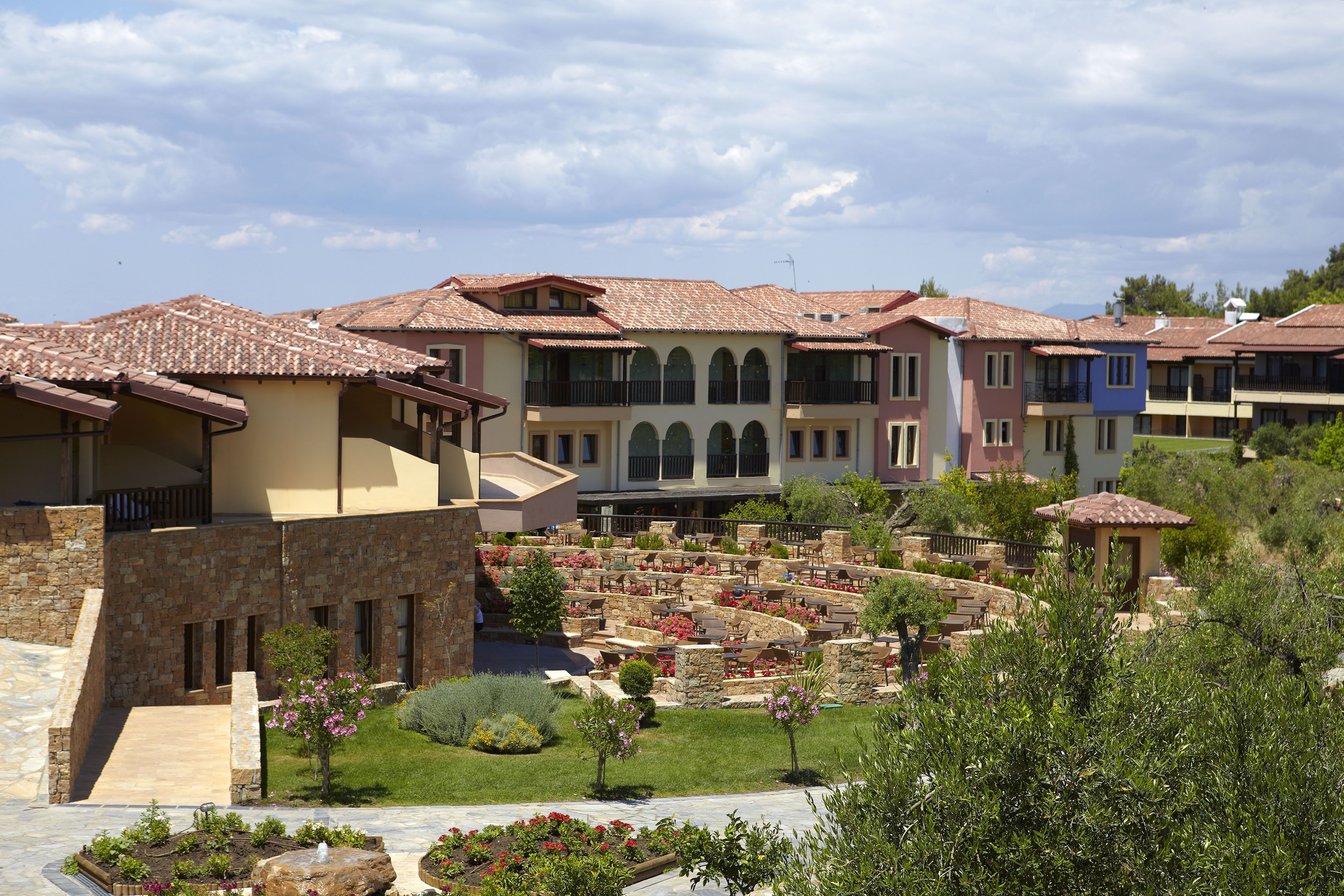 A courtyard with a stone pathway, a fountain, and a variety of plants.