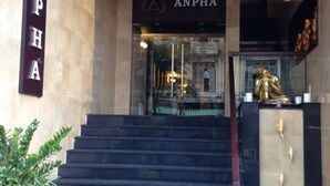 L’entrée d’un immeuble, avec une enseigne portant l’inscription « ANPHA » et une statue dorée sur les marches.