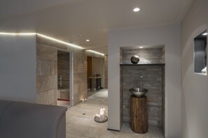 Une salle de bain moderne avec un mur en pierre, un lavabo et un tabouret en bois.