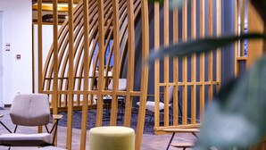 A modern interior with a wooden partition, round tables, and chairs. - Hotel le Caballin (Vogelgrun)