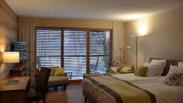 Habitación de hotel con una cama grande, un escritorio con lámpara, una silla y una ventana con persianas.