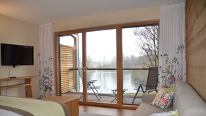 A room with a bed, a sofa, a TV, and a balcony with a table and chairs. - Hotel le Caballin (Vogelgrun)